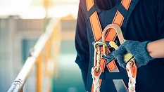 Construction worker wearing safety harness and safety line working at high place.