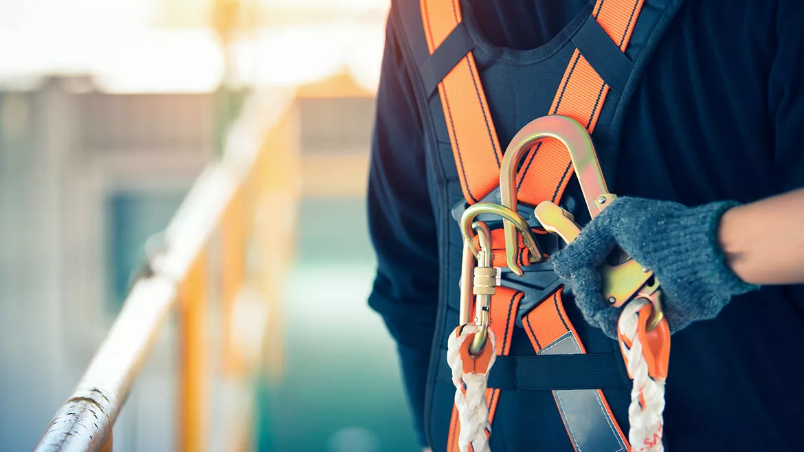 Construction worker wearing safety harness and safety line working at high place.