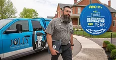 Daniel, a plumber with Jolly Plumbing, walking away from a Jolly work truck, a house in the background.