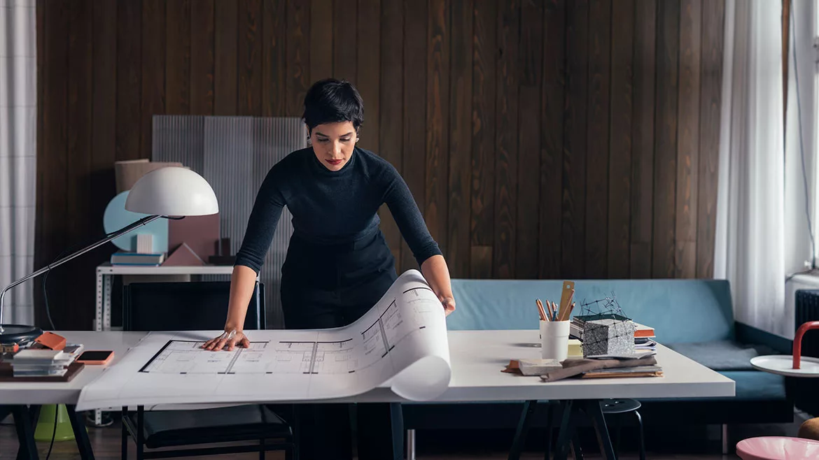 Female architect working at her modern studio looking at plans.