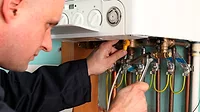 Plumber adjusting a boiler's pipes A plumber adjusting a boiler's pipes with a wrench and turning a valve.