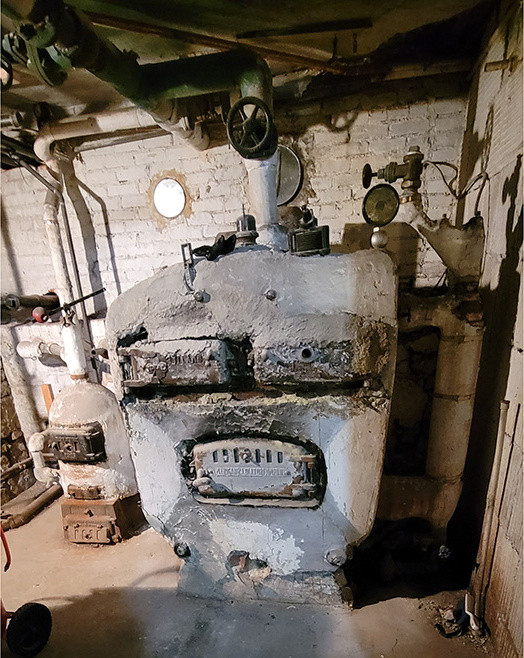 Old boiler in a basement covered in light gray material.