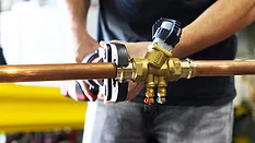 Close up of contractor using a wrench on piping.