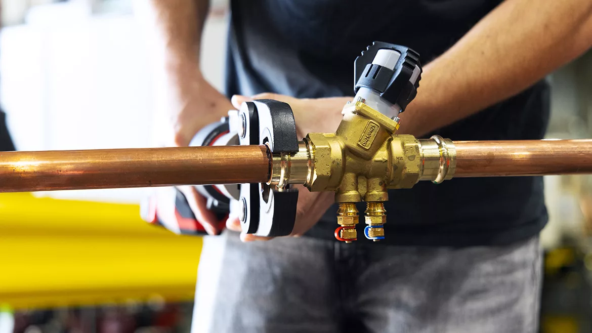 Close up of contractor using a wrench on piping.