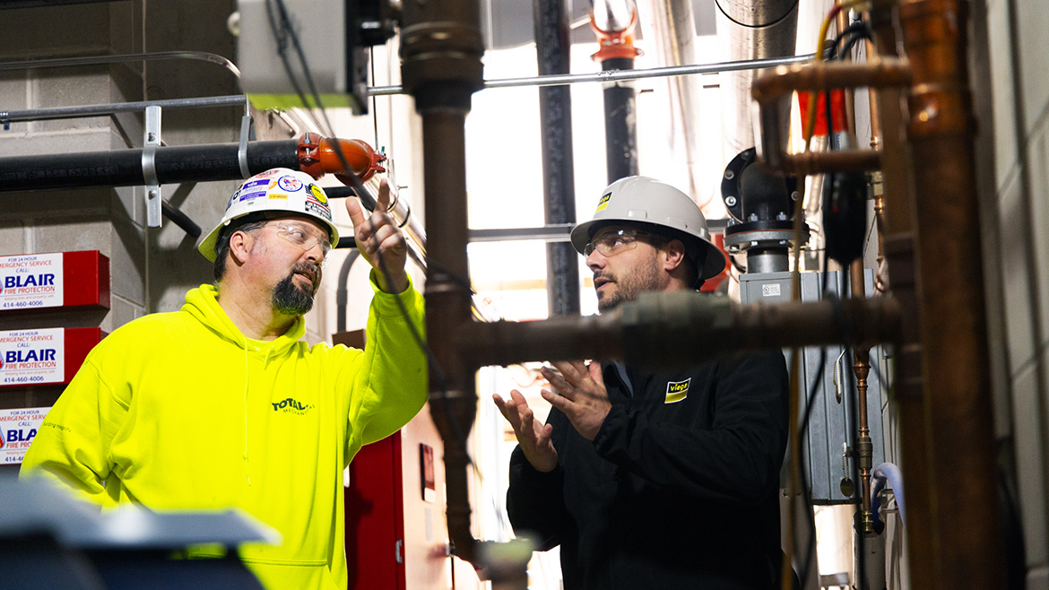 Two workers wearing safety hats having a discussion in a worksite.