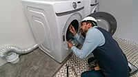 Handyman installing a washing machine at a house.