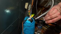 Air Conditioner technician using a brazing torch to repair equipment.