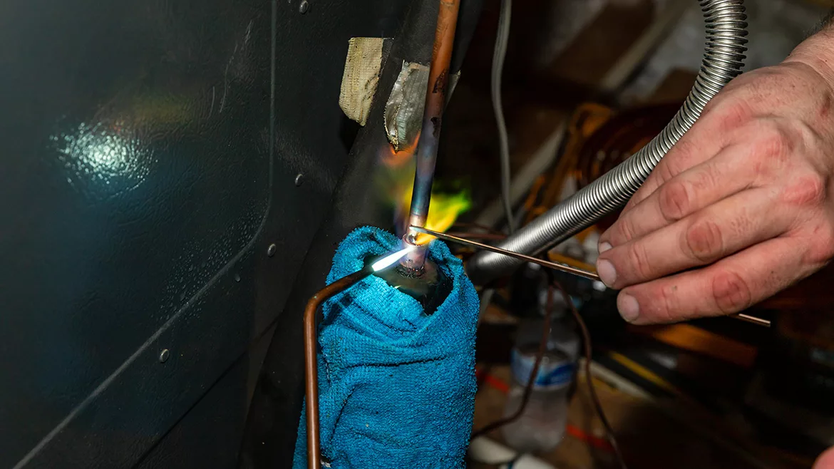 Air Conditioner technician using a brazing torch to repair equipment.