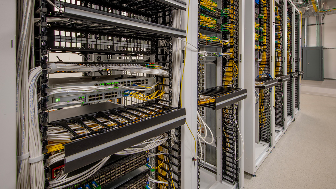 Server room with racks and fiber optic connections.