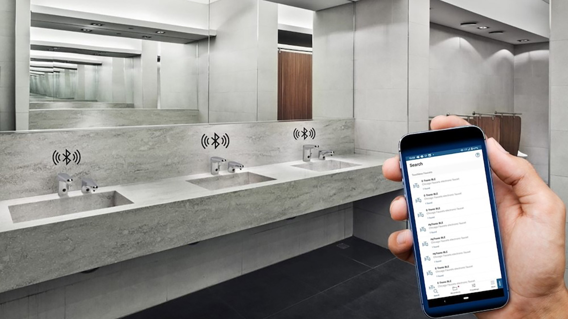 A public bathroom with the Bluetooth icon over each touchless faucet and a close-up of a hand holding a mobile phone showing Bluetooth networks.