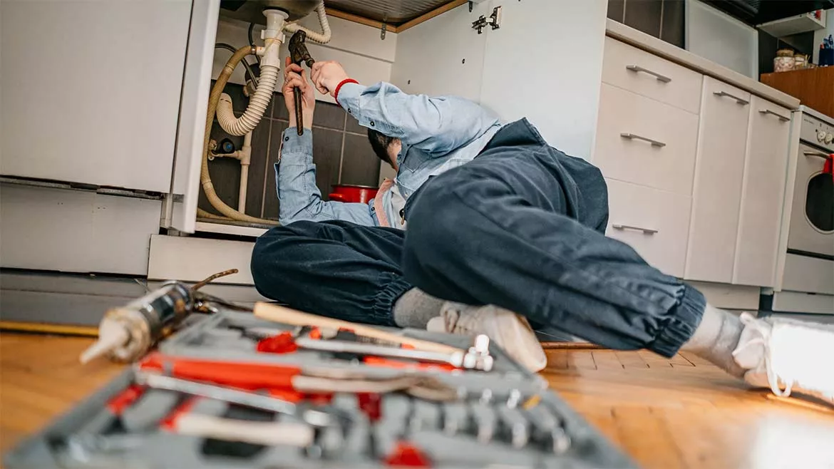 Plumber Working under Sink