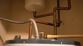 Various copper pipes and tubes from above a water heating boiler unit.