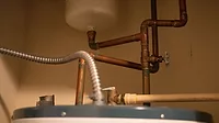 Various copper pipes and tubes from above a water heating boiler unit.
