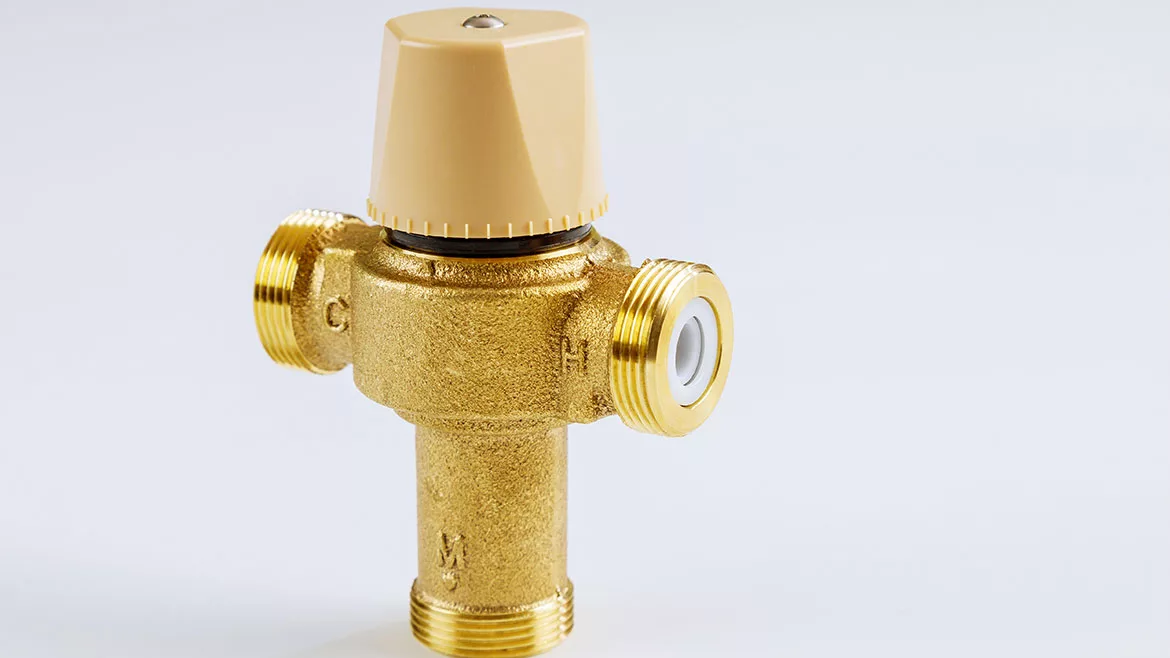 Plumbing connection with close up water brass thermostatic mixing valve isolated on white background.
