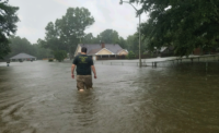 Jason Horcasitas, A.H. Deveney’s inside sales manager, wades through flood waters near his home, which was damaged severely