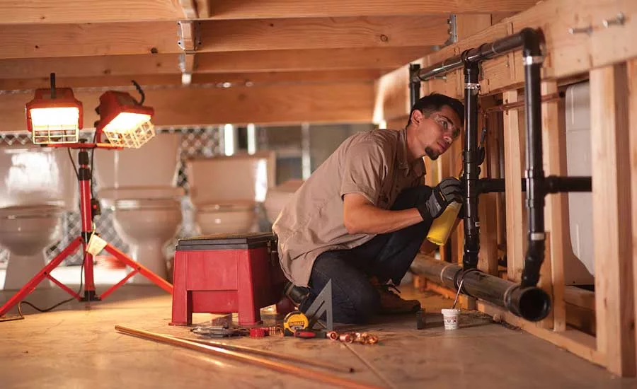Jairo Serrano sweats pipe in one of the school’s bathroom modules