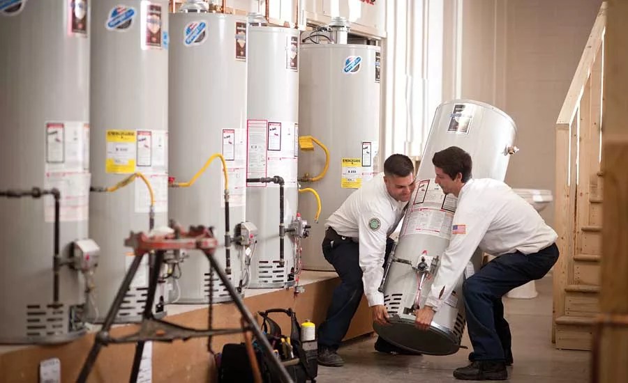 From left to right: Students Jared Colegrave and Dekota Everhart lift a water heater into place